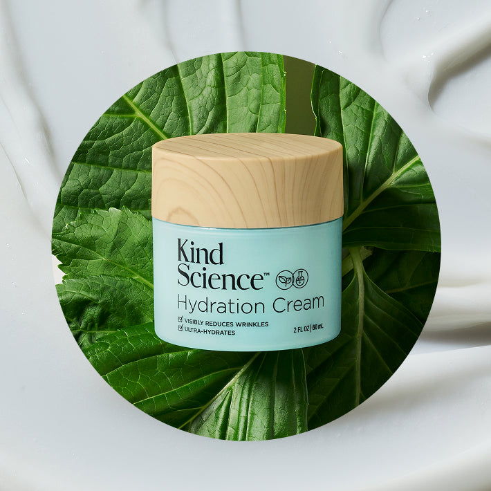 Kind Science Hydration Cream jar with wooden cap on a leafy green background