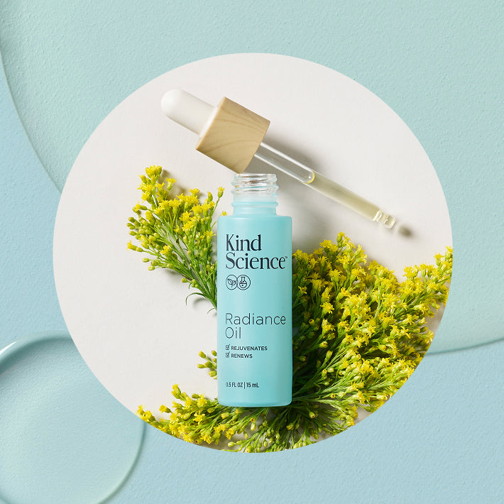 Kind Science Radiance Oil bottle with dropper on a bed of Moringa flowers, which are shown to Improve radiance + signs of aging with vitamins A, C + E.